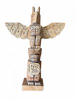 Front view of entire wooden totem pole showing carved details and wings