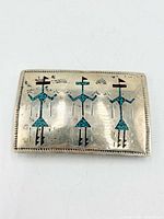Front of sterling silver buckle showing three turquoise chip inlay figures and stamped border