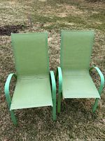 pair of green metal patio lawn chairs on lawn