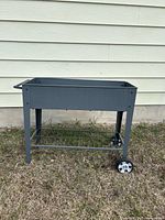 overall view of gray metal raised planter on legs with wheels and shelf