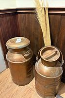 Both copper milk churns side by side showing overall appearance