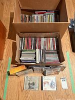 Full view of two large boxes filled with CD jewel cases plus several CDs in front