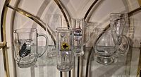 Group shot of seven clear glass beer mugs and glasses on shelf