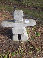 Full view of concrete Inukshuk statue in garden