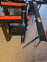 Blue steel sawhorse folded beside black/orange plastic sawhorse