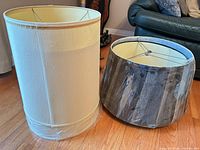 Two lampshades, beige cylindrical and dark drum