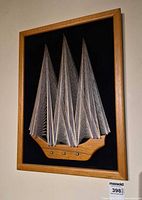 Full view of framed sailboat string art within wood frame
