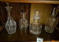 All four decanters on shelf showing overall condition and presence or absence of stoppers