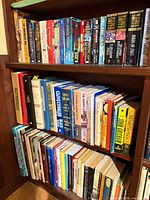Three shelves filled with assorted hardcover and paperback books