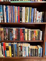 Three shelves packed with mixed hardcover and paperback books in various genres