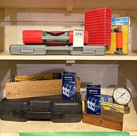 Two shelf lot showing all items including grey socket set case, red cylinder, Starrett box, microtorch, black laser kit case, hobby chisel block, Spinlock boxes, dial gauge and wooden box