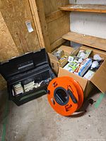 Toolbox, box of packaged bulbs, orange extension cord reel