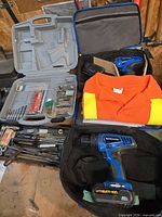 Overall lot view showing drill, bit case, carry bag, chisels, and work shirt