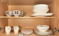 Cabinet showing full assortment: square plates, serving bowls, soup mugs, white mugs