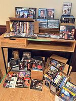 Overall view of Philips player with numerous DVDs and VHS tapes on and below wooden surface