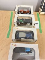 Four boxed Signature Models cars stacked on table