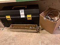 Toolbox closed with adjacent cardboard boxes of plumbing parts