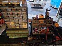 Overall lot showing plastic drawer cabinet, three metal cases, tool caddy, charger