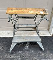 Full view of folding Workmate workbench showing frame, wooden top, crank handles