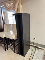 Full view of tall black shelving unit beside chairs
