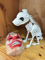 Skeleton dog figure and clown mask on shelf