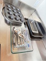 All items grouped on countertop: muffin pan, baking sheets, loaf pans, glass dish, bag of spoons
