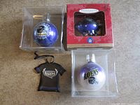 Front view showing all four ornaments: two in clear boxes, one Hallmark boxed, one jersey ornament
