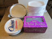 Assorted disposable catering items including forks, plates, pans and trays