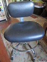 Front view of black padded office chair on chrome base with casters