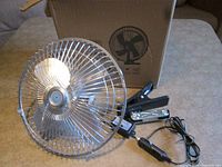 Fan, clamp base, power cord and plug displayed in front of box