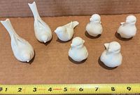 Seven Lenox white porcelain bird figurines lined with ruler for scale