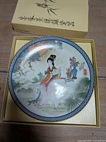 Plate in box showing lady scene and blue rim pattern
