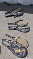 All three Wilson Hammer series racquets with covers laid out on pavement