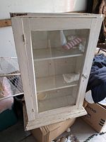 Front view of cabinet showing glass door, shelves and overall paint wear