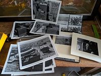 Overview of assorted black-and-white prints, some mounted, spread on table