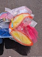 Top view of lot showing orange-yellow wings, pink tutu, blue tutu and packaged items