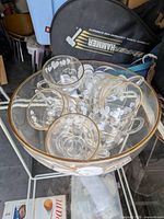 punch bowl filled with matching cups showing etched motif and gold rims