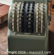 Front view showing full adding machine with five wheel columns and gray housing