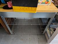 Full view of table front showing butcher block top, frame, one visible wire shelf and casters