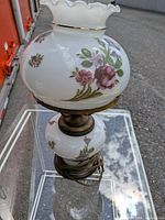 Full view of milk glass hurricane lamp showing upper shade, lower globe, brass base, and cord