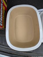Interior of stoneware roasting pan showing beige unglazed surface and white speckled rim