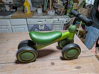 Left side view of entire ride-on toy showing frame, wheels and handlebar