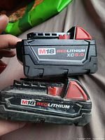 Two Milwaukee M18 batteries stacked showing model labels