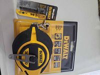 Front view of sealed DeWalt measuring tape package with carabiner and socket adapter visible