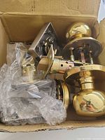 Box containing polished brass door knobs, latch and hardware