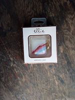 Front of retail box showing Ellie pastel AirPods case with gold keyring