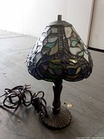 Full view of stained glass table lamp showing shade colors, metal base and electric cord