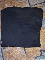 Folded black tank top laid flat on floor