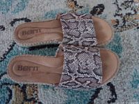 Top view of pair of Born Drilles snakeskin print wedge sandals on patterned rug