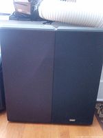 Front view of the two Camber speakers showing black grille cloth and logo